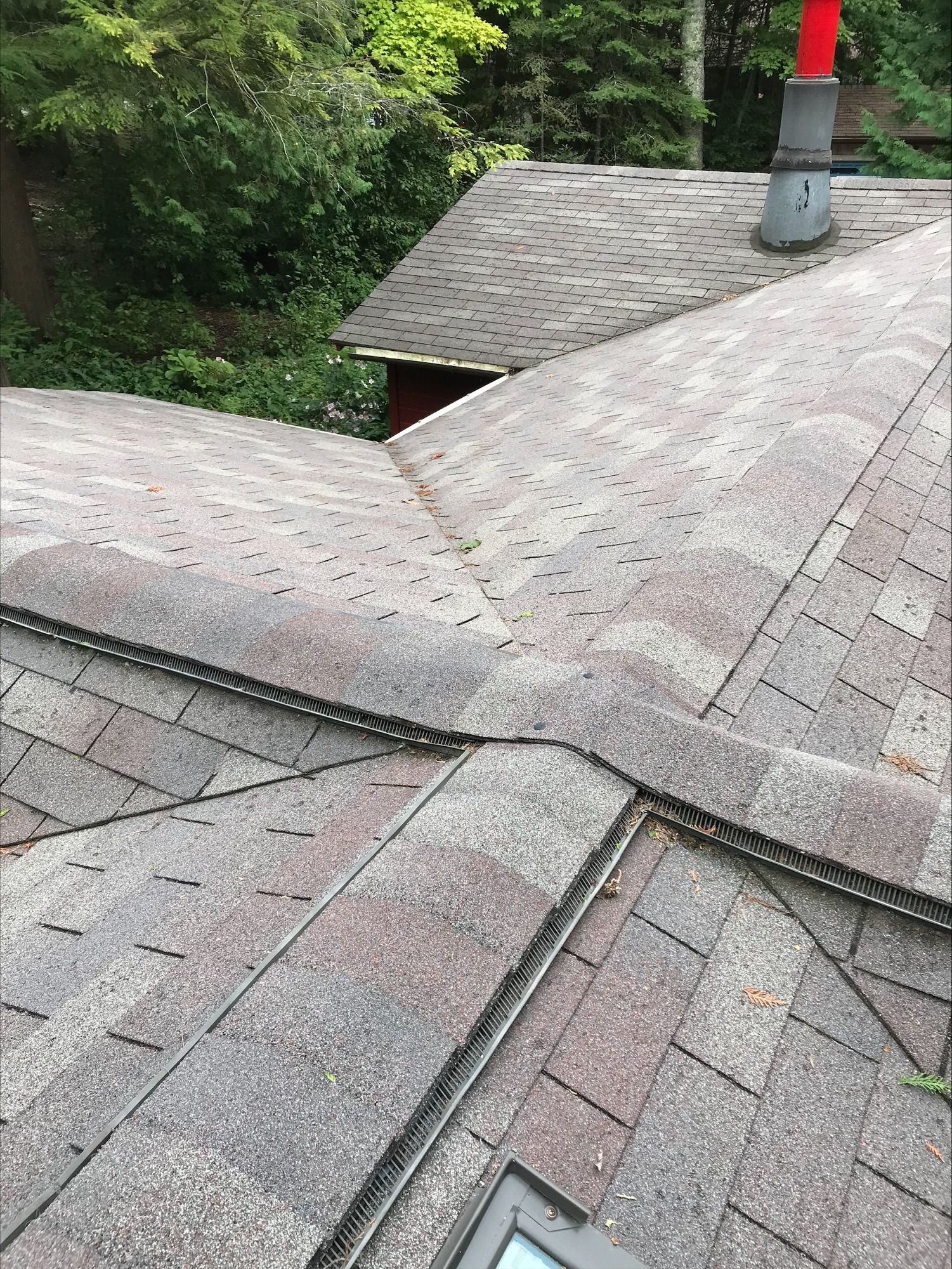 A roof with a skylight and a chimney on it.