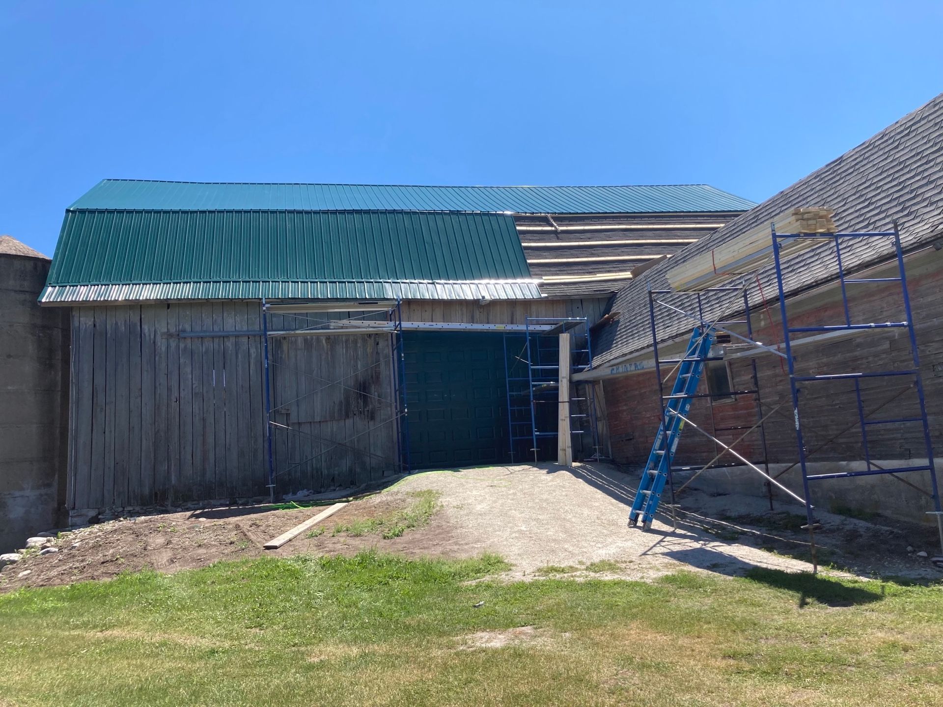A barn with a green roof is being remodeled.