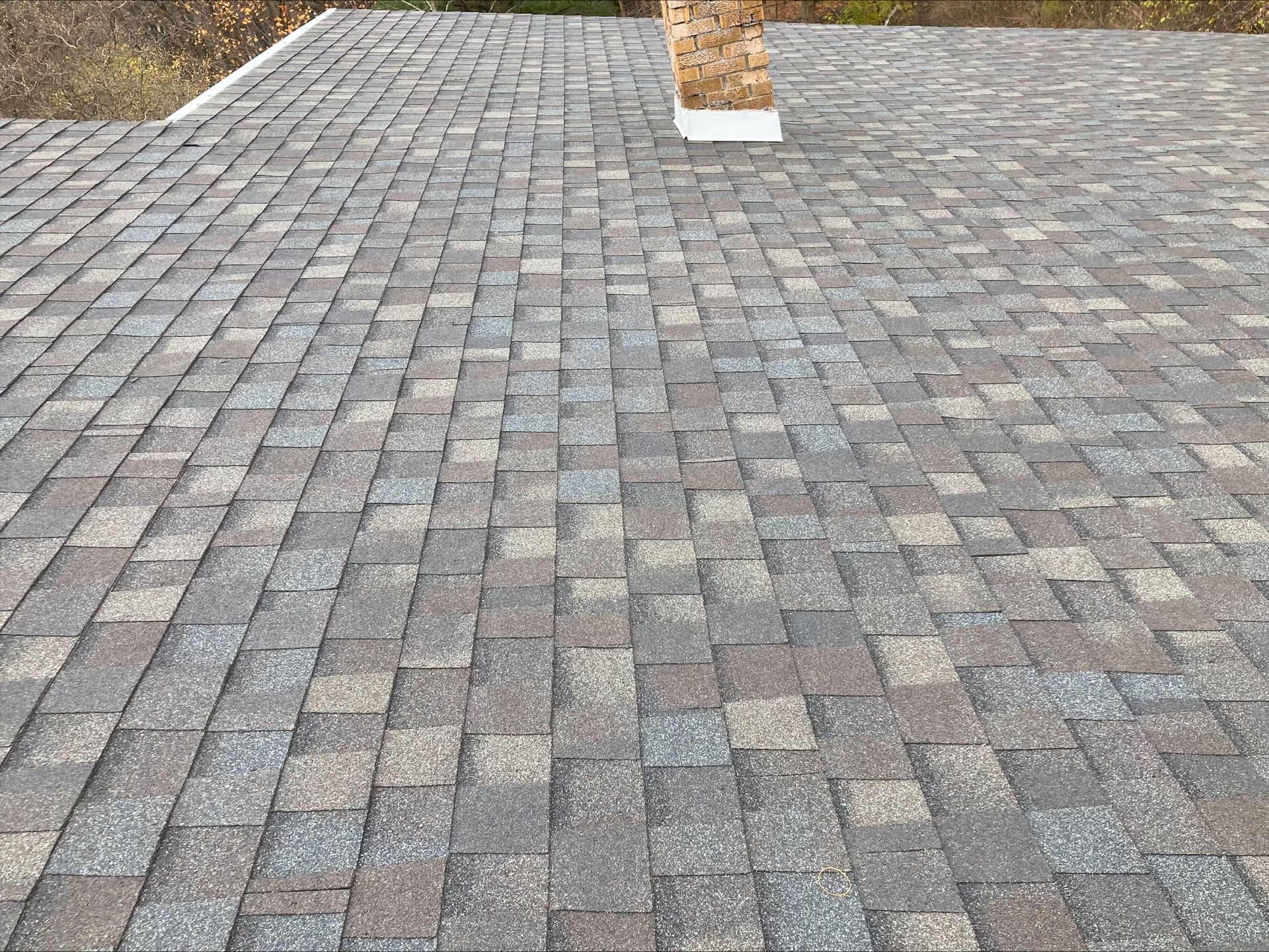 A close up of a roof with shingles and a chimney.