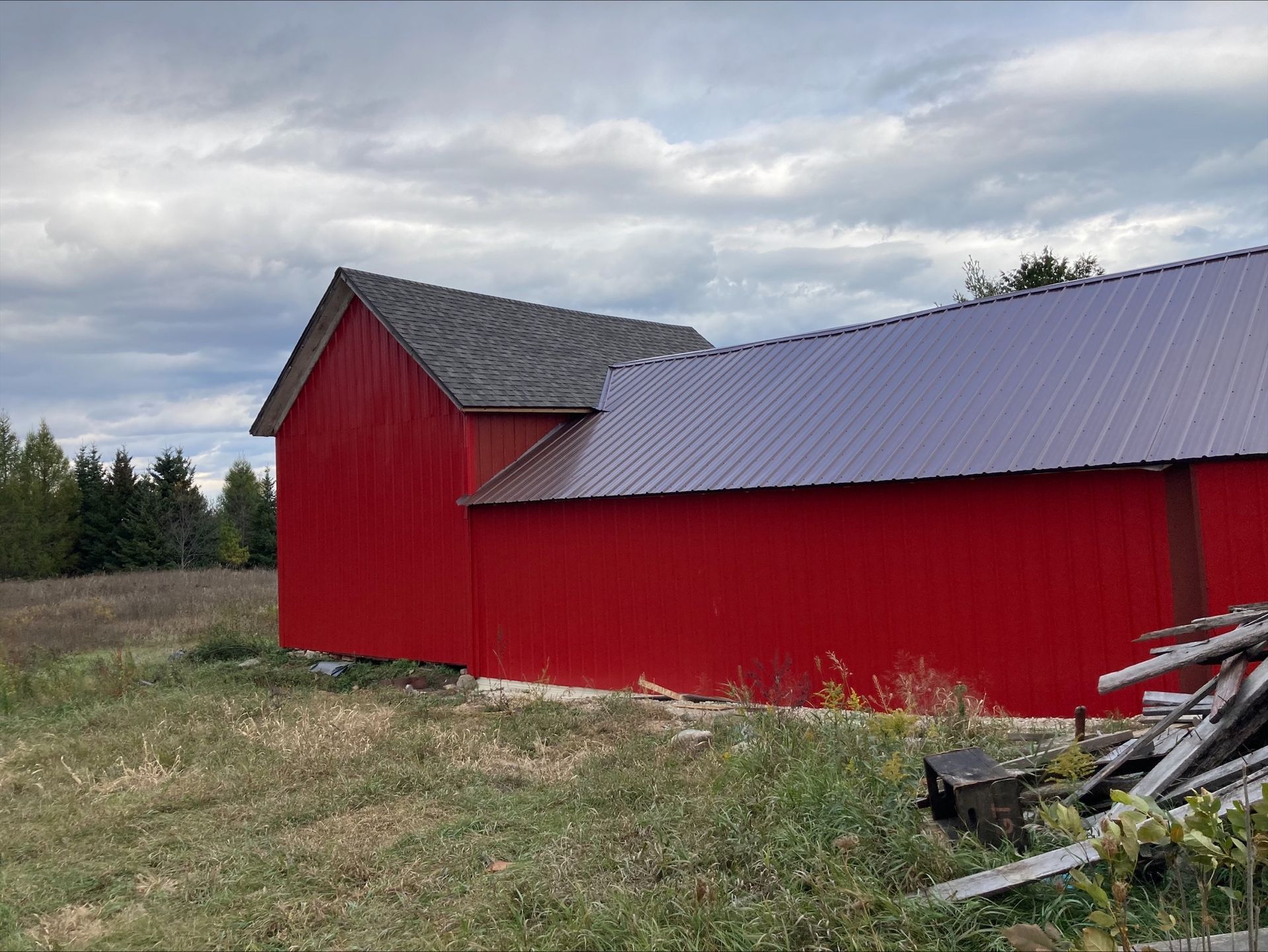 A red barn with a purple roof is in a field.