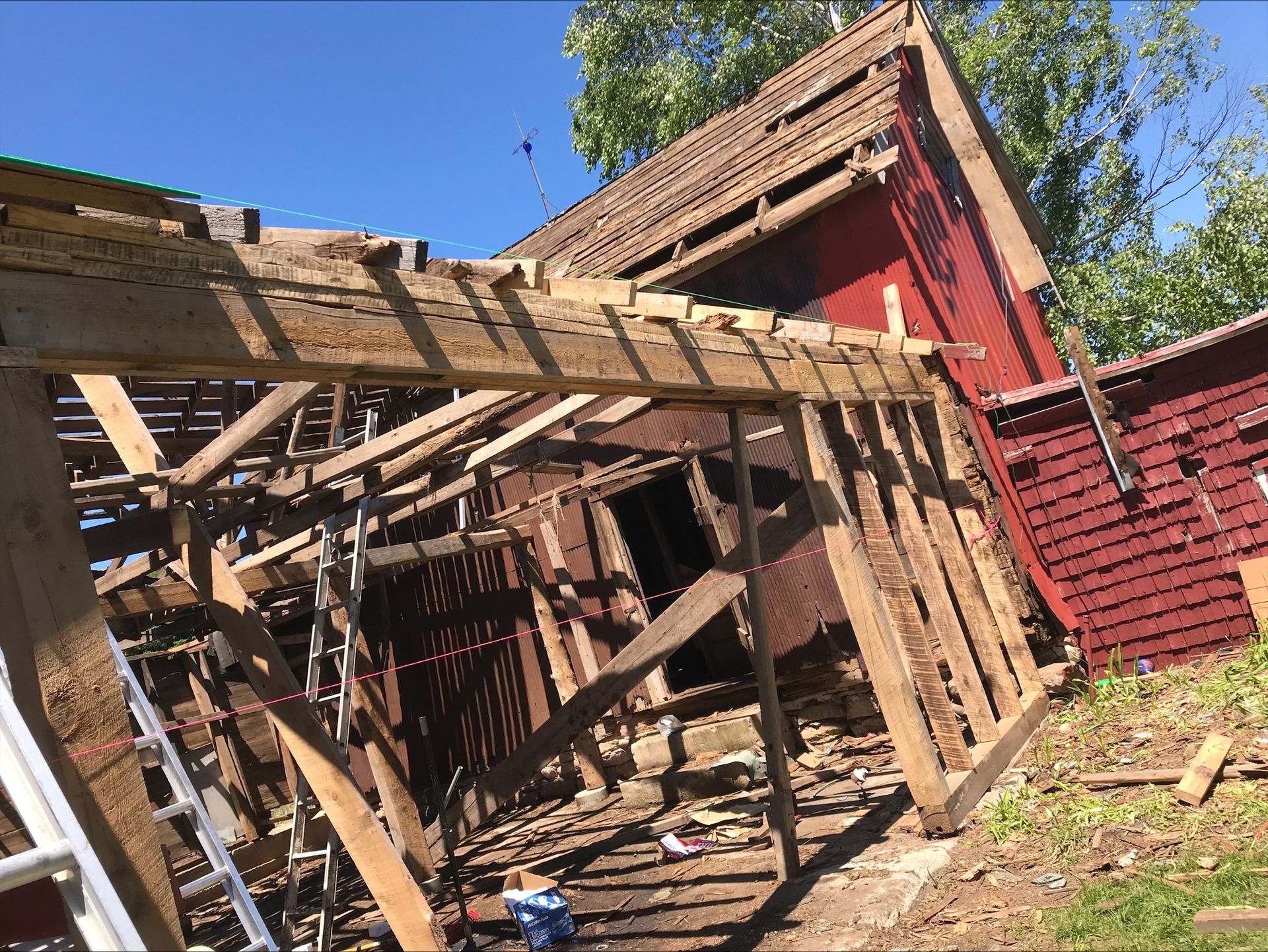 A wooden structure is being demolished with a ladder in the foreground.