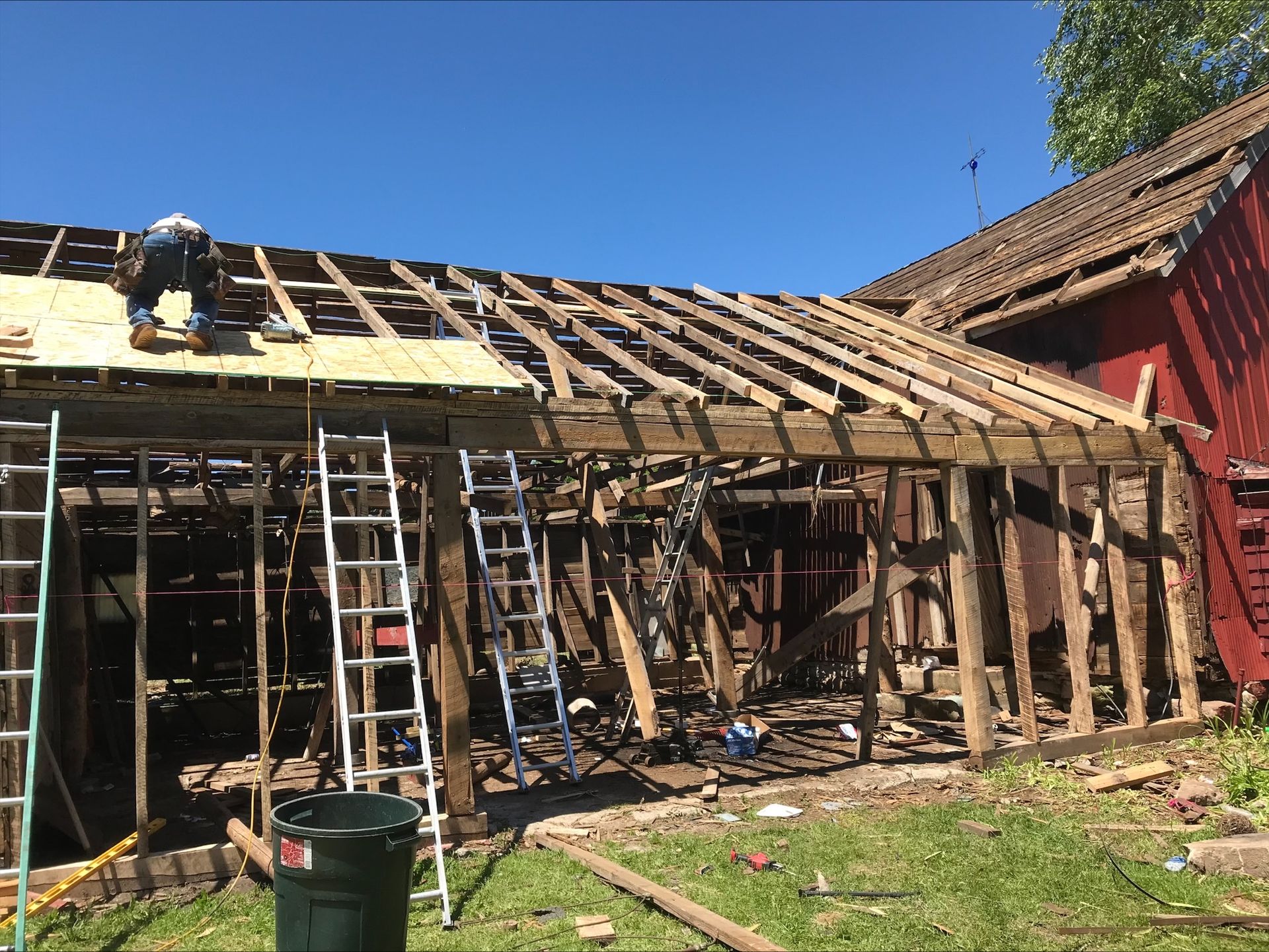 A man is working on the roof of a barn.