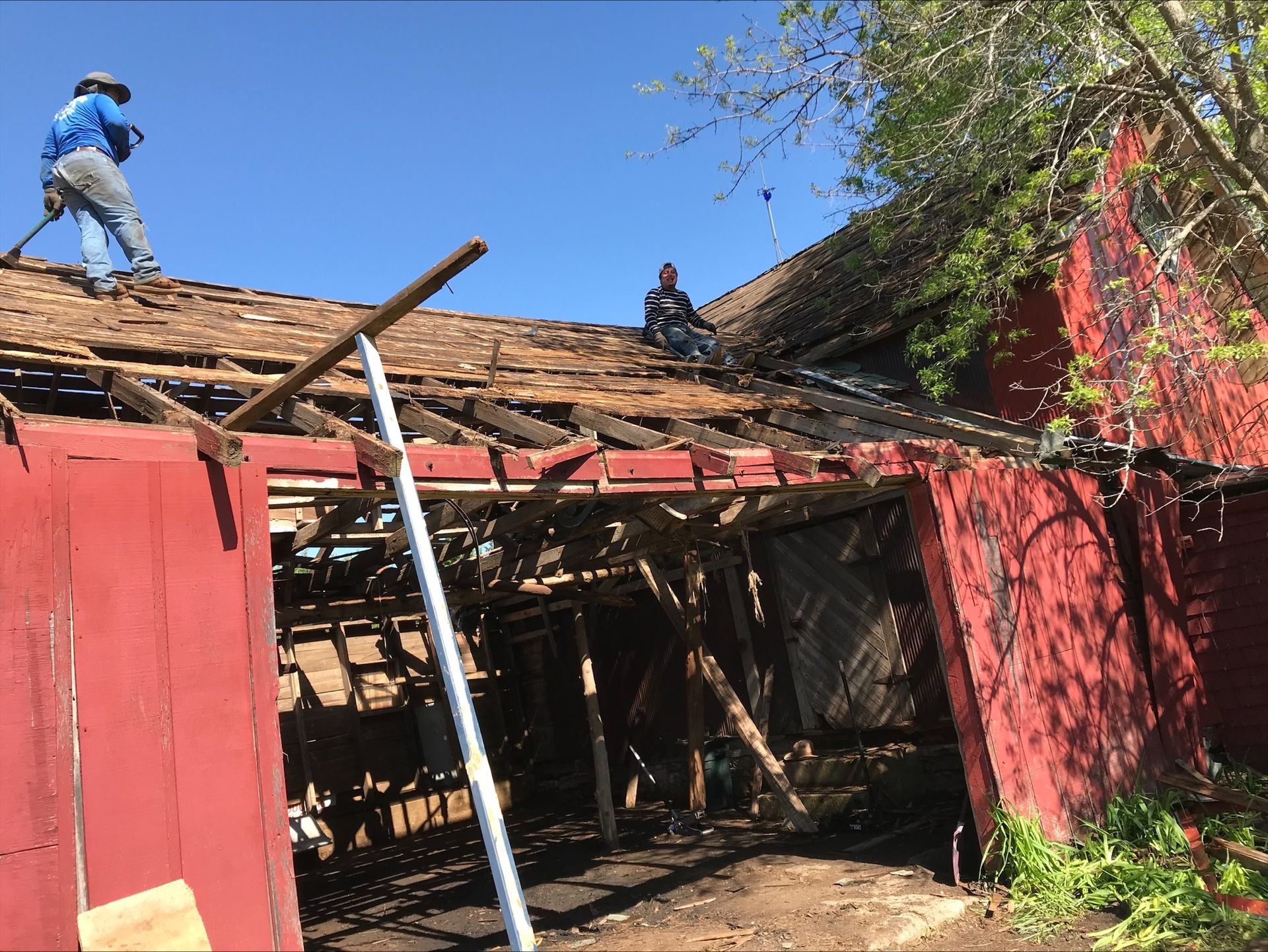 Two men are working on the roof of a red building.