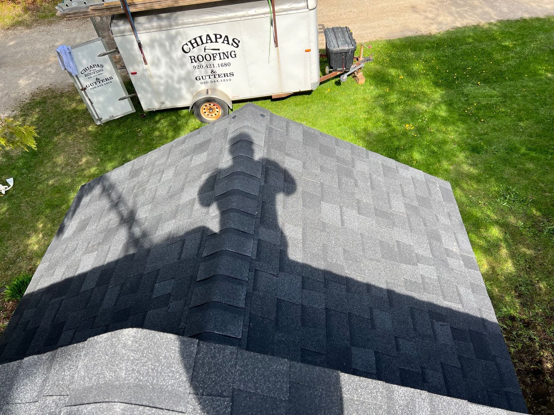 An aerial view of a roof with a shadow of a person on it.
