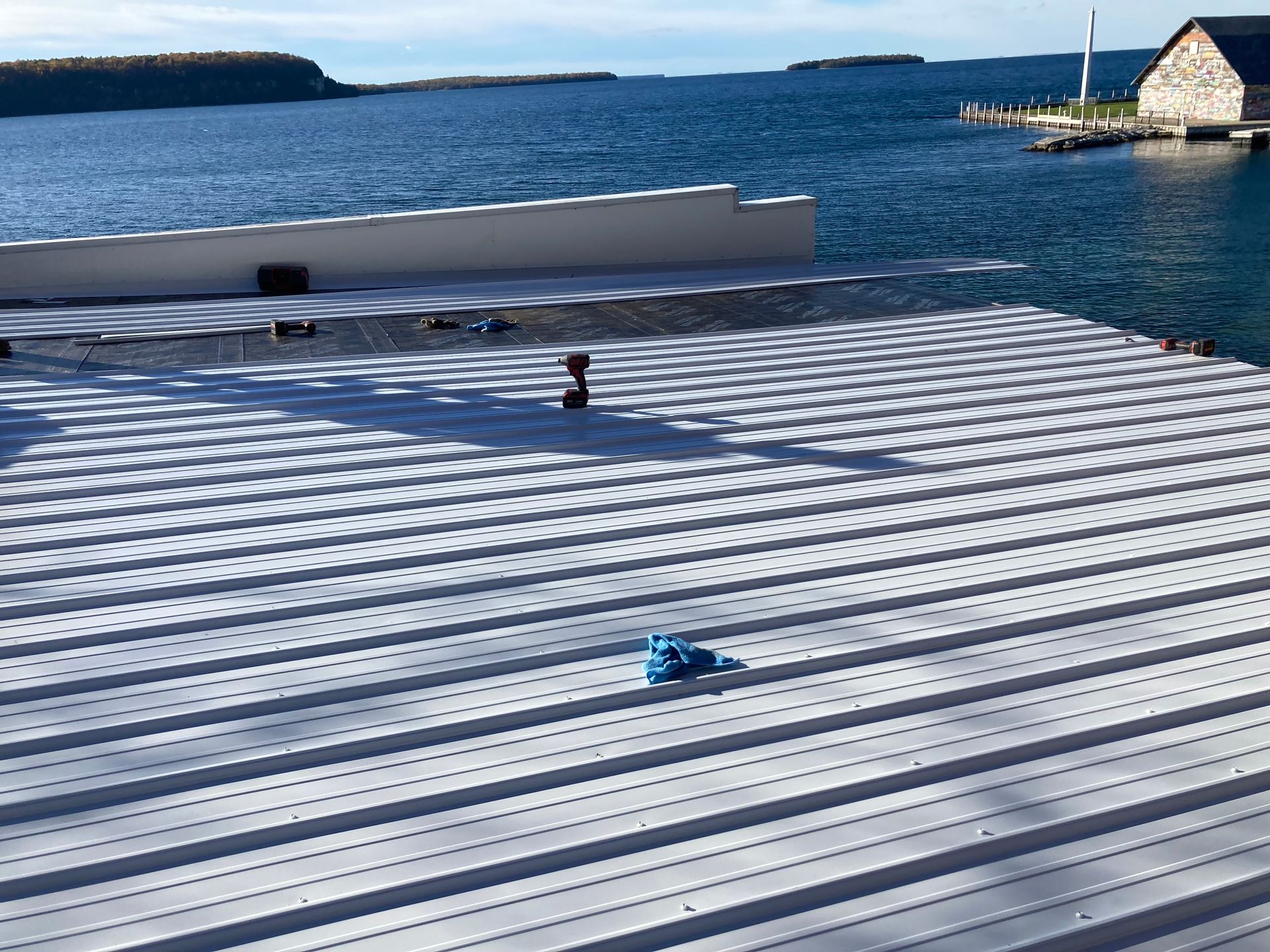 A roof with a view of the ocean and a building in the background.
