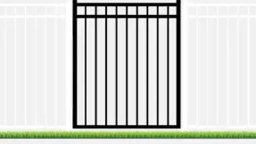 Black metal gate in a white fence with green grass.