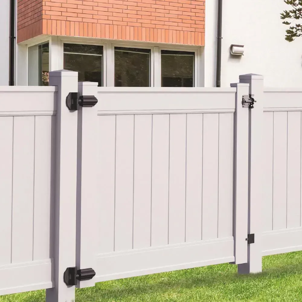 White vinyl fence with gate, black latches, in front of a brick house.