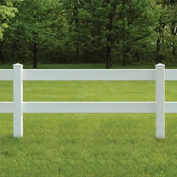 White two-rail fence in a grassy field, with trees in the background.
