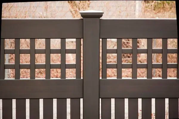 Brown wooden gate with a lattice design and vertical slats.