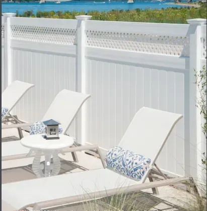 White lounge chairs by a white fence, overlooking the water.