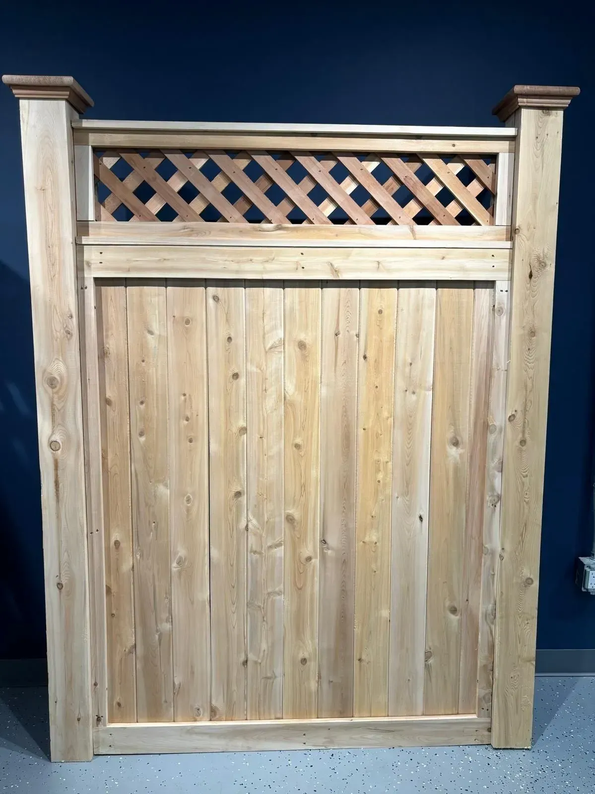 Wooden fence panel with lattice top. Natural wood color against a dark blue background.