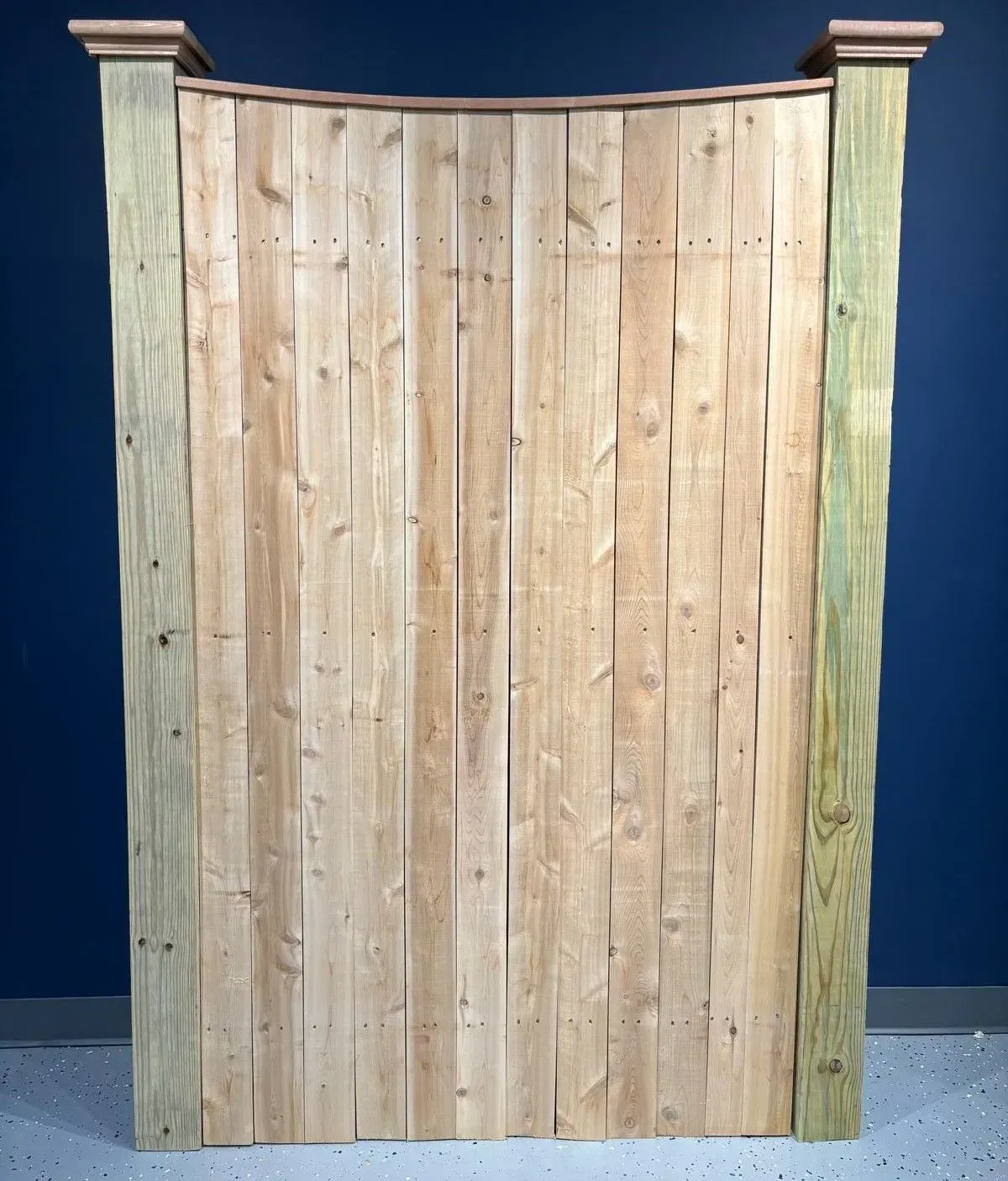 Wooden fence with curved top and decorative posts.