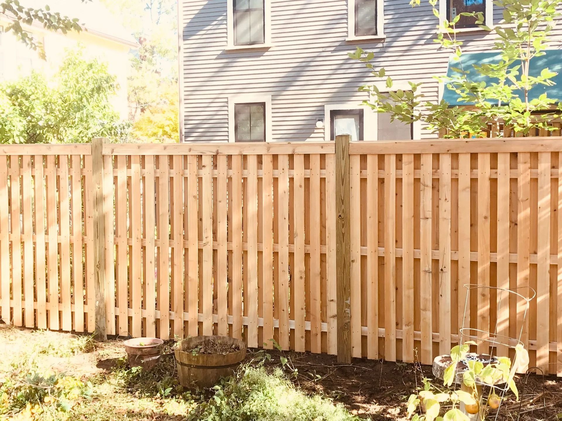 Wooden fence in a backyard, with a house in the background.