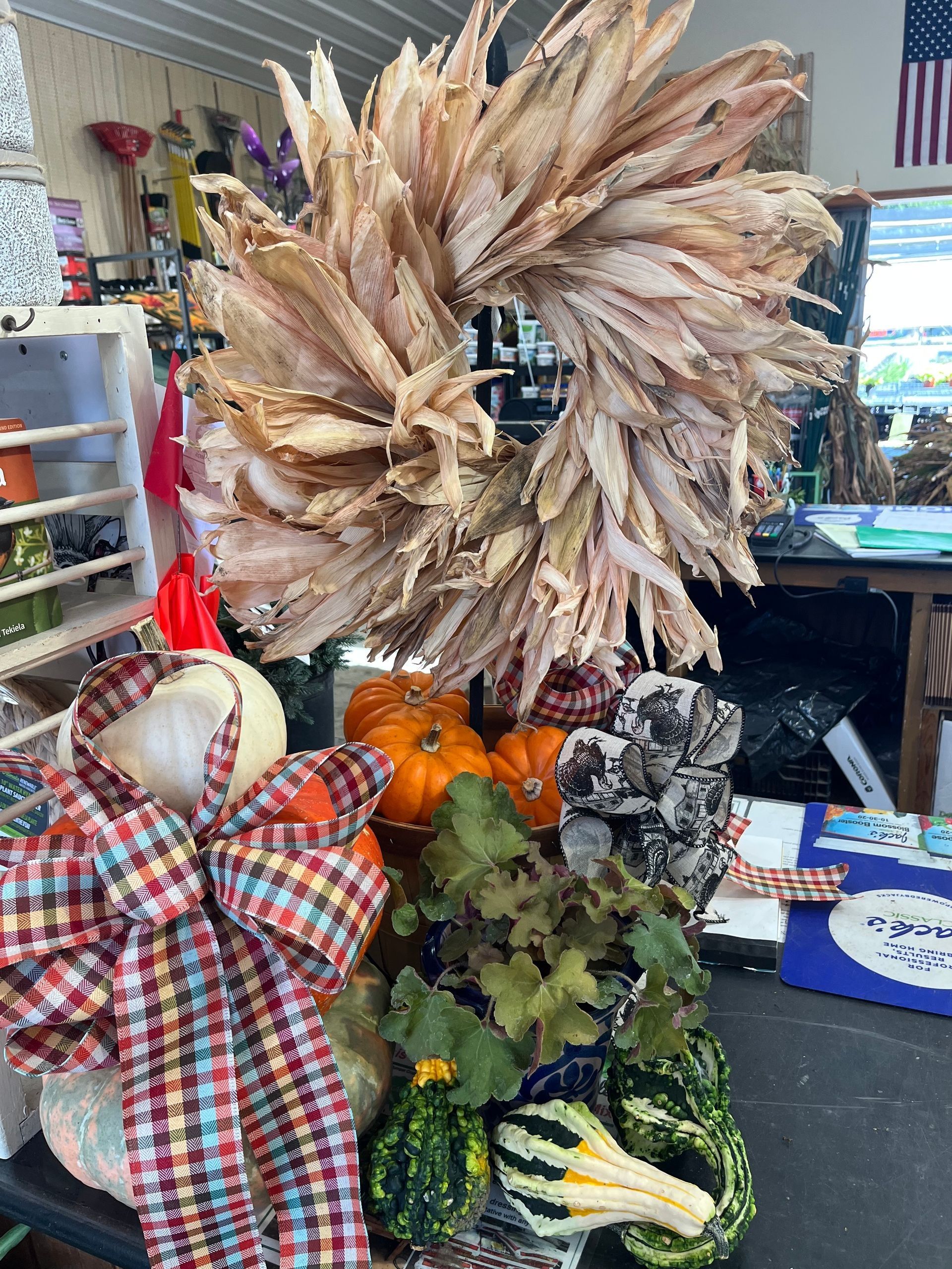 Fall display with wreath, pumpkins, gourds, and plaid bow.