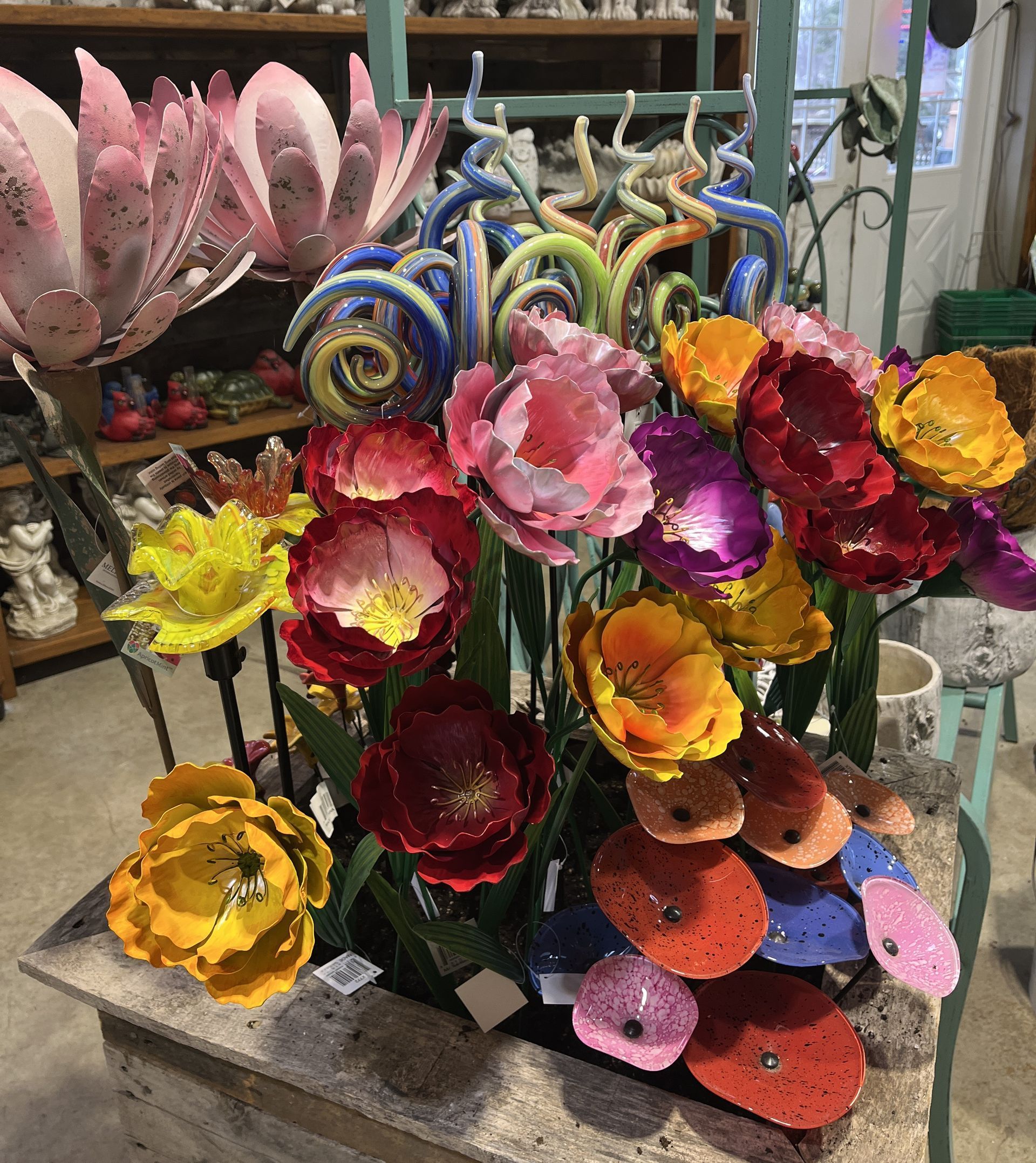 Colorful metal flower sculptures in a shop setting.