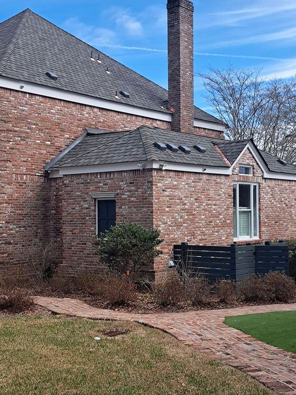 Brick building with red brick, gray roof, tall chimney, and a brick pathway.