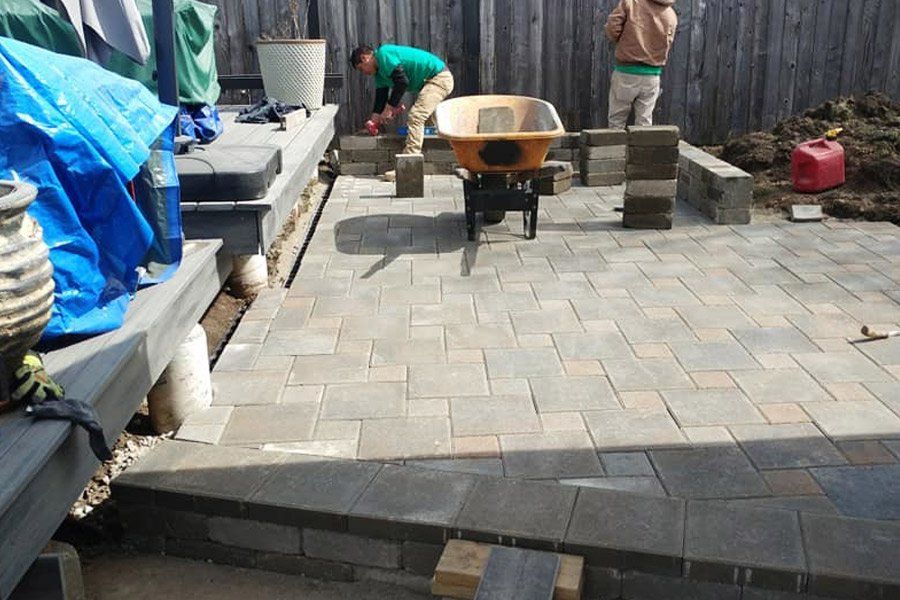 two men are working on a patio with a wheelbarrow