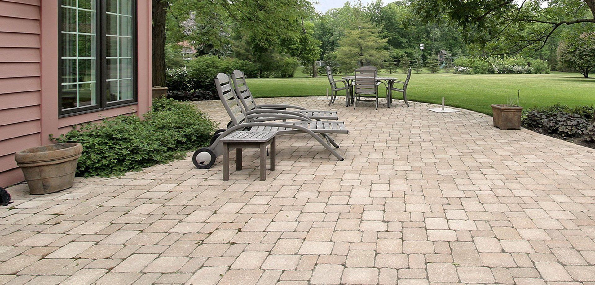 A patio with chairs and a table in front of a house.