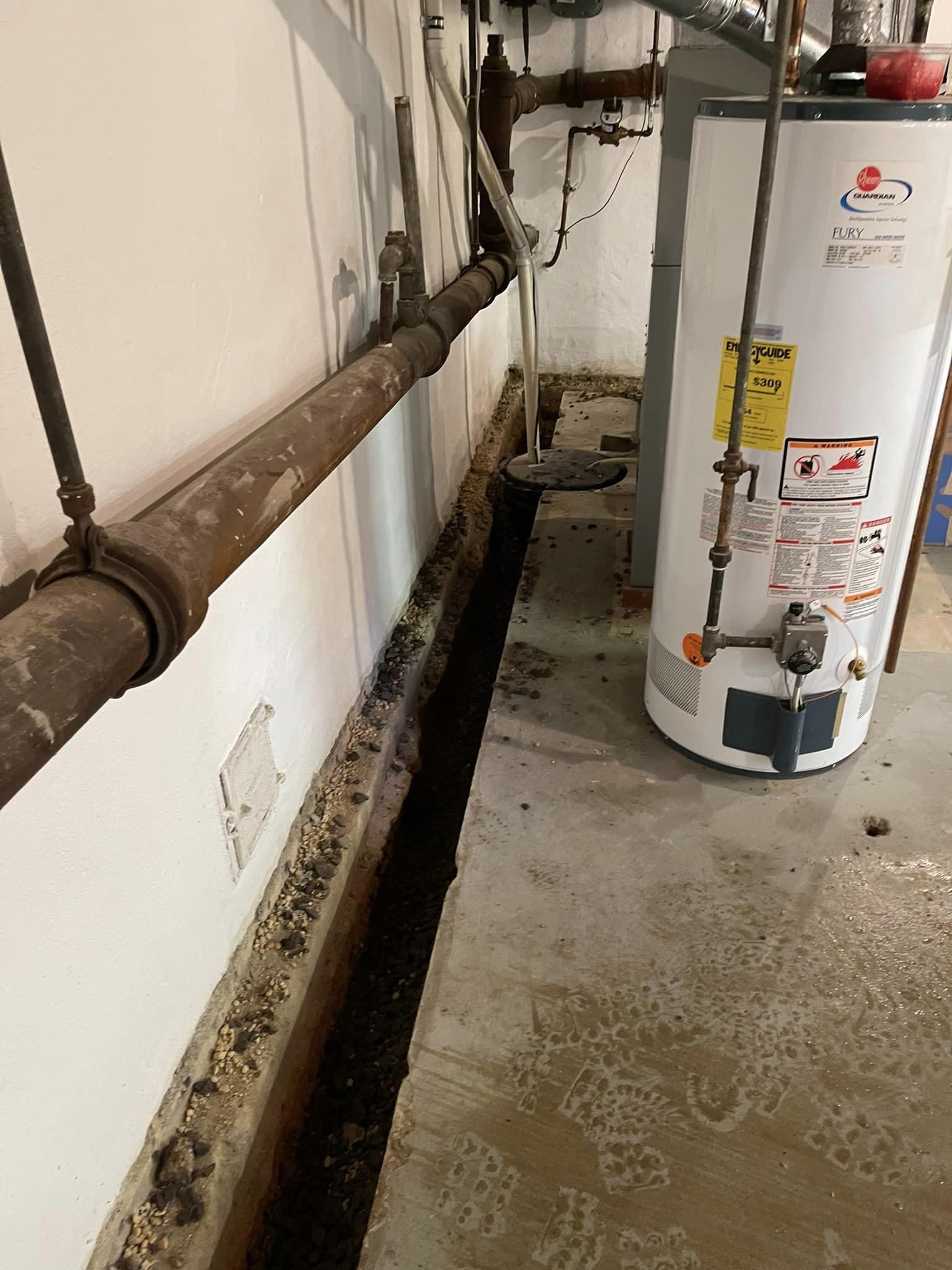 A water heater is sitting in a basement next to a wall.