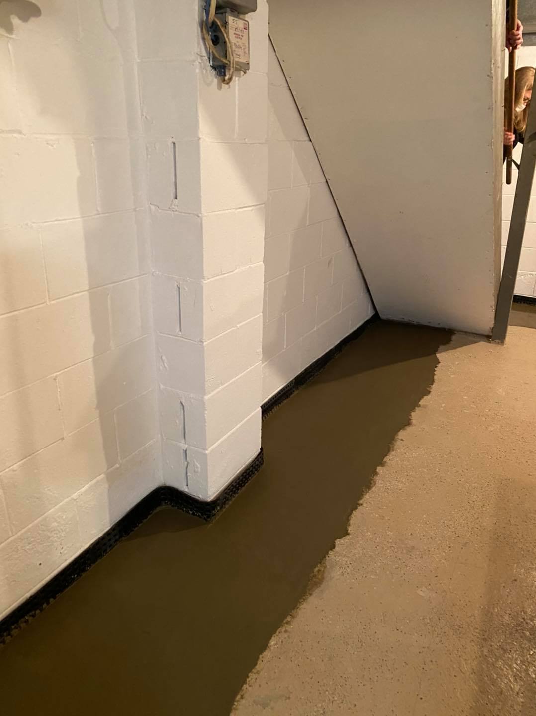 A basement with a concrete floor and a white brick wall.