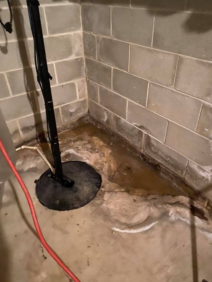 A flooded basement with a sump pump in the corner.