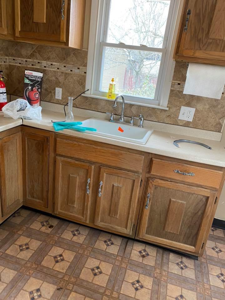 A kitchen with wooden cabinets , a sink , and a window.