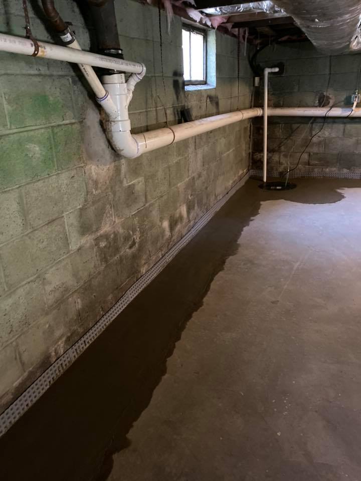 A basement with a lot of pipes and a window.