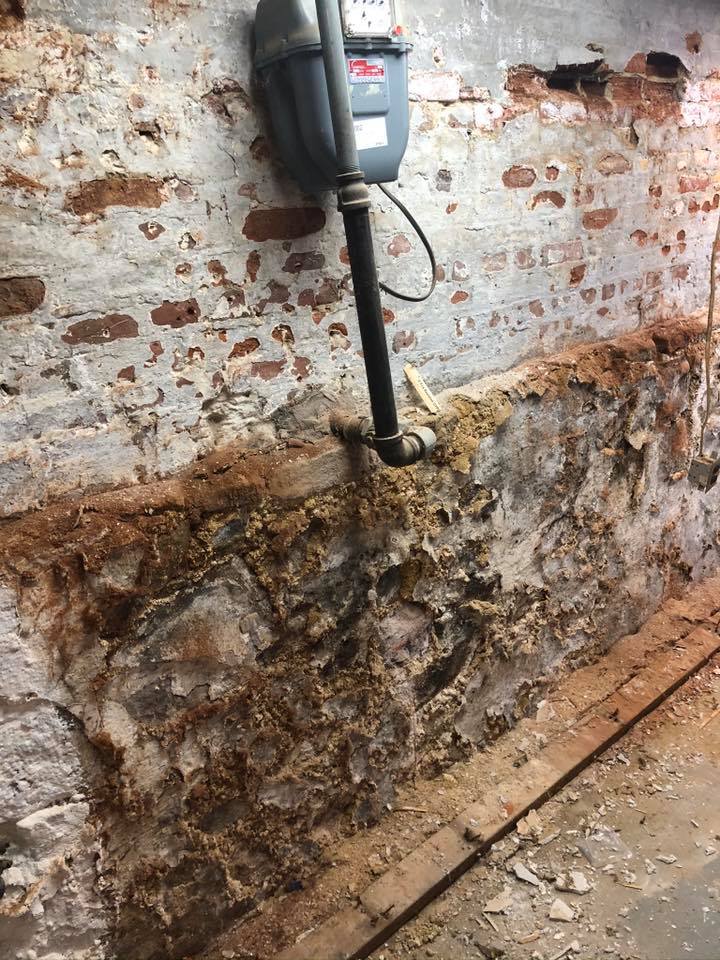 A brick wall with a pipe coming out of it.