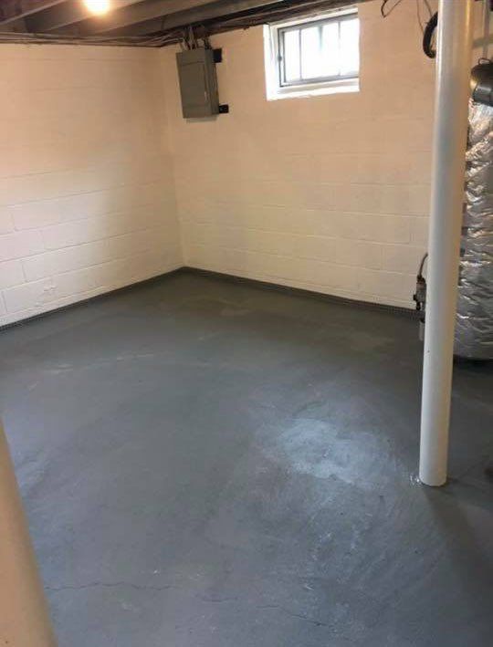 An empty basement with a gray floor and white walls.