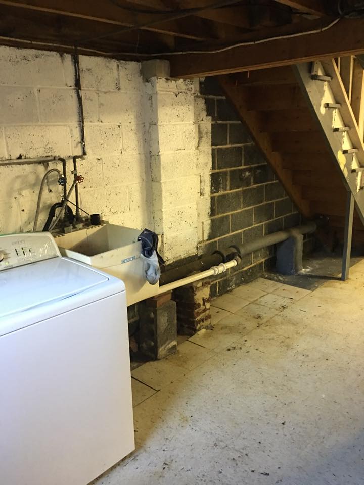 A washer and dryer are in a basement with stairs.