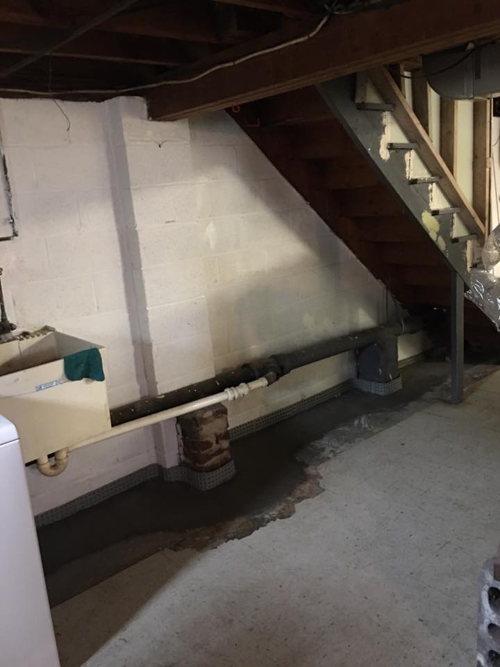 A basement with stairs and a sink in it.