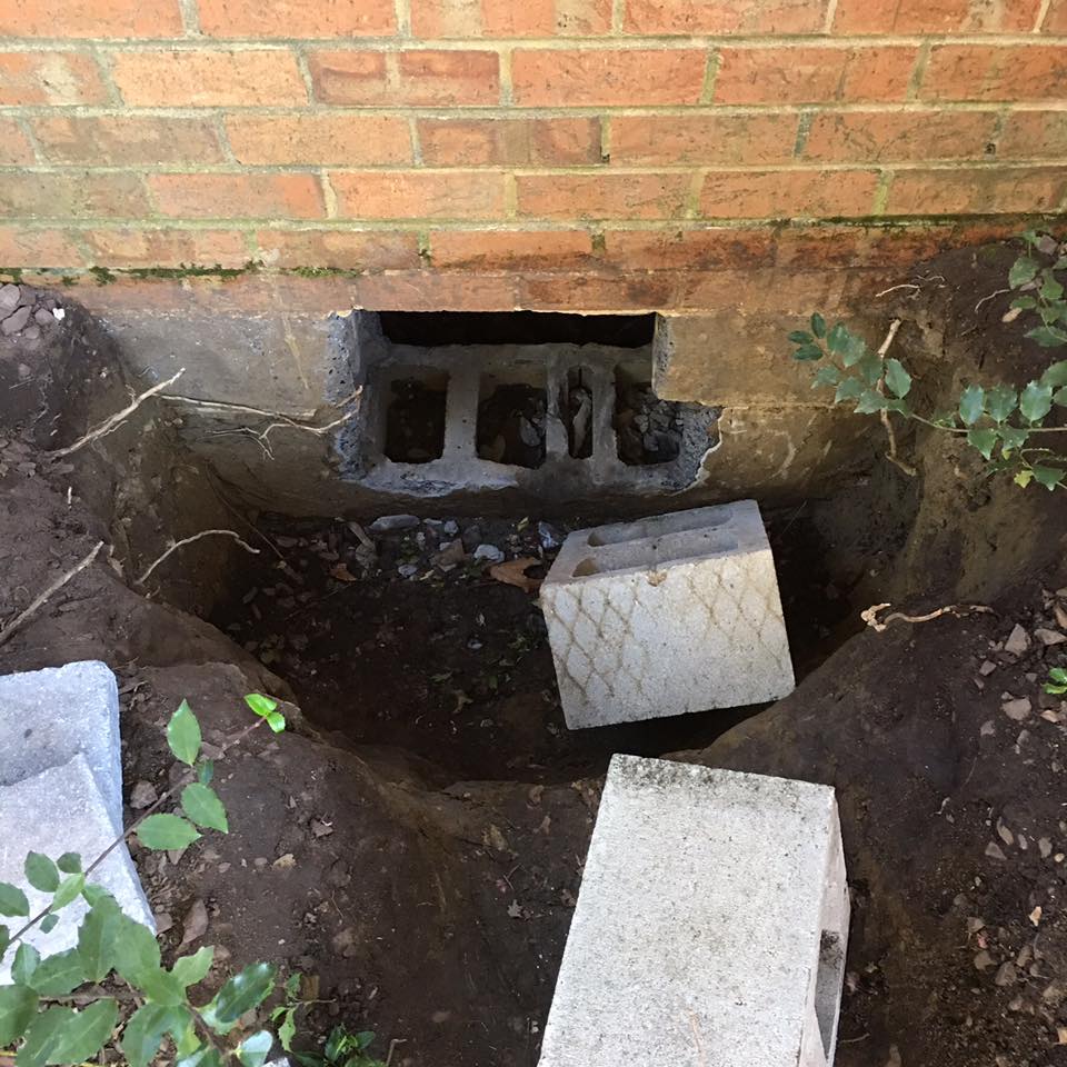 A hole in a brick wall is being filled with concrete blocks