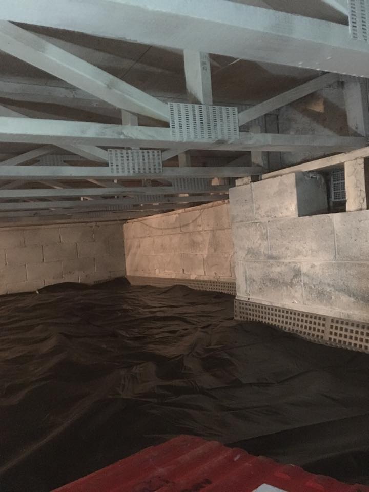 An empty basement with a black bag on the floor.