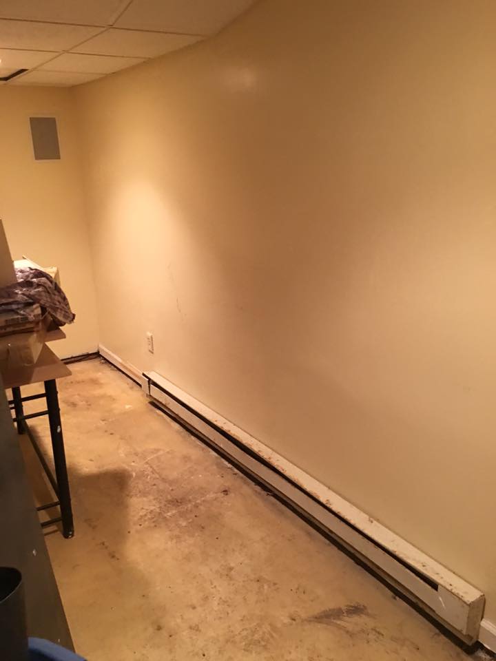 A room with a white wall and a heater on the floor