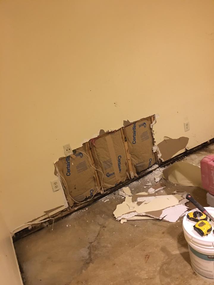 A room with a hole in the wall and a bucket of paint.