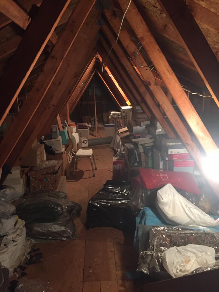An attic filled with lots of luggage and boxes.