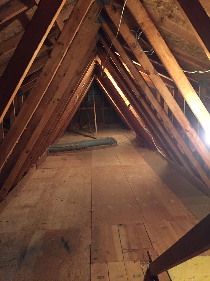 An attic with wooden beams and a light on the ceiling.