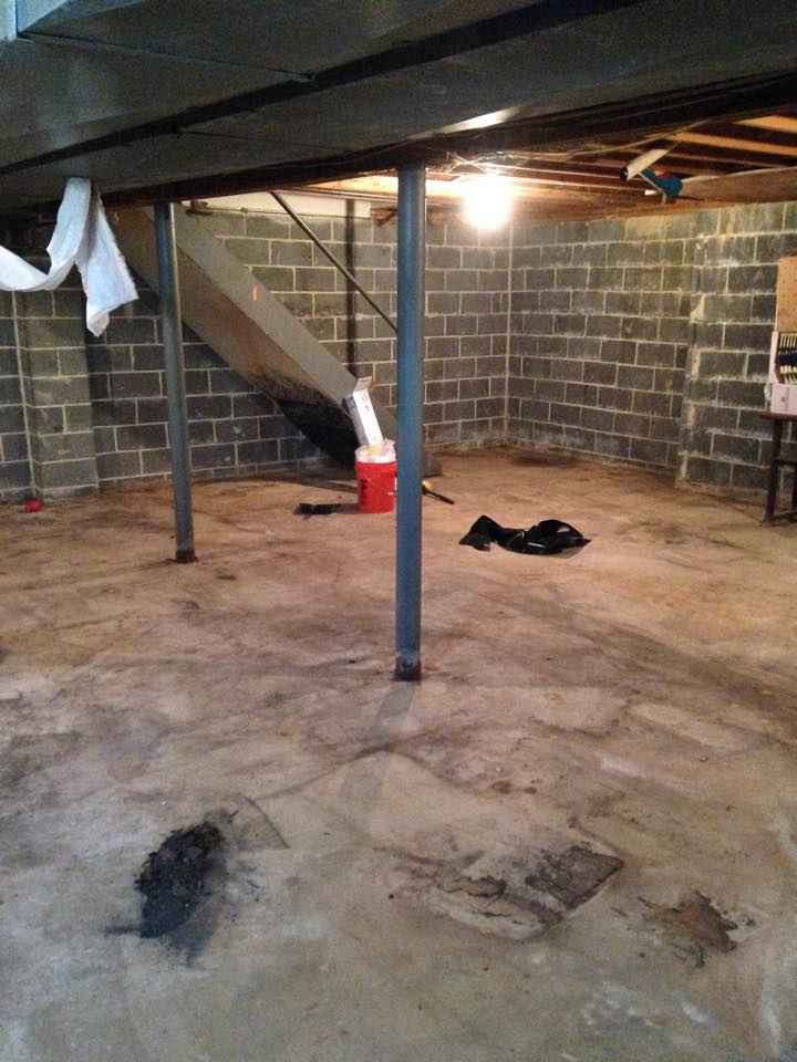 A basement with stairs and a vacuum cleaner on the floor.