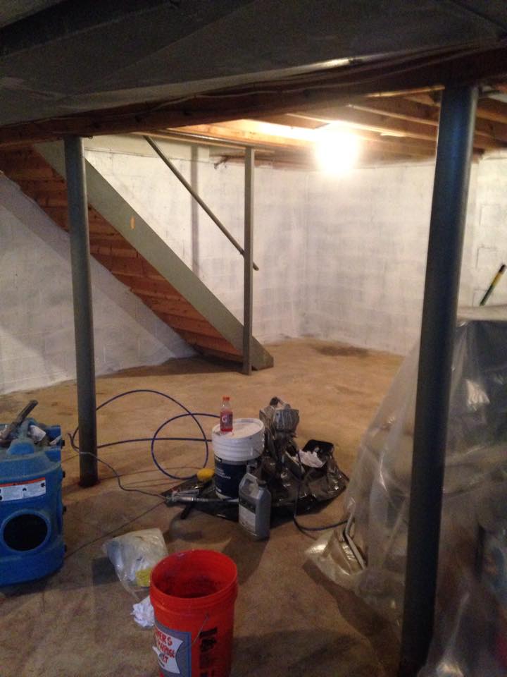 A basement with stairs and a vacuum cleaner on the floor.