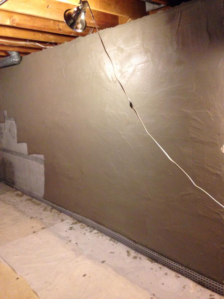 A concrete wall in a basement with a lamp on the ceiling.