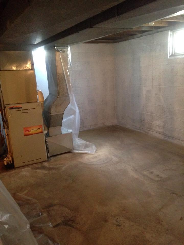 An empty basement with a furnace and air conditioner.