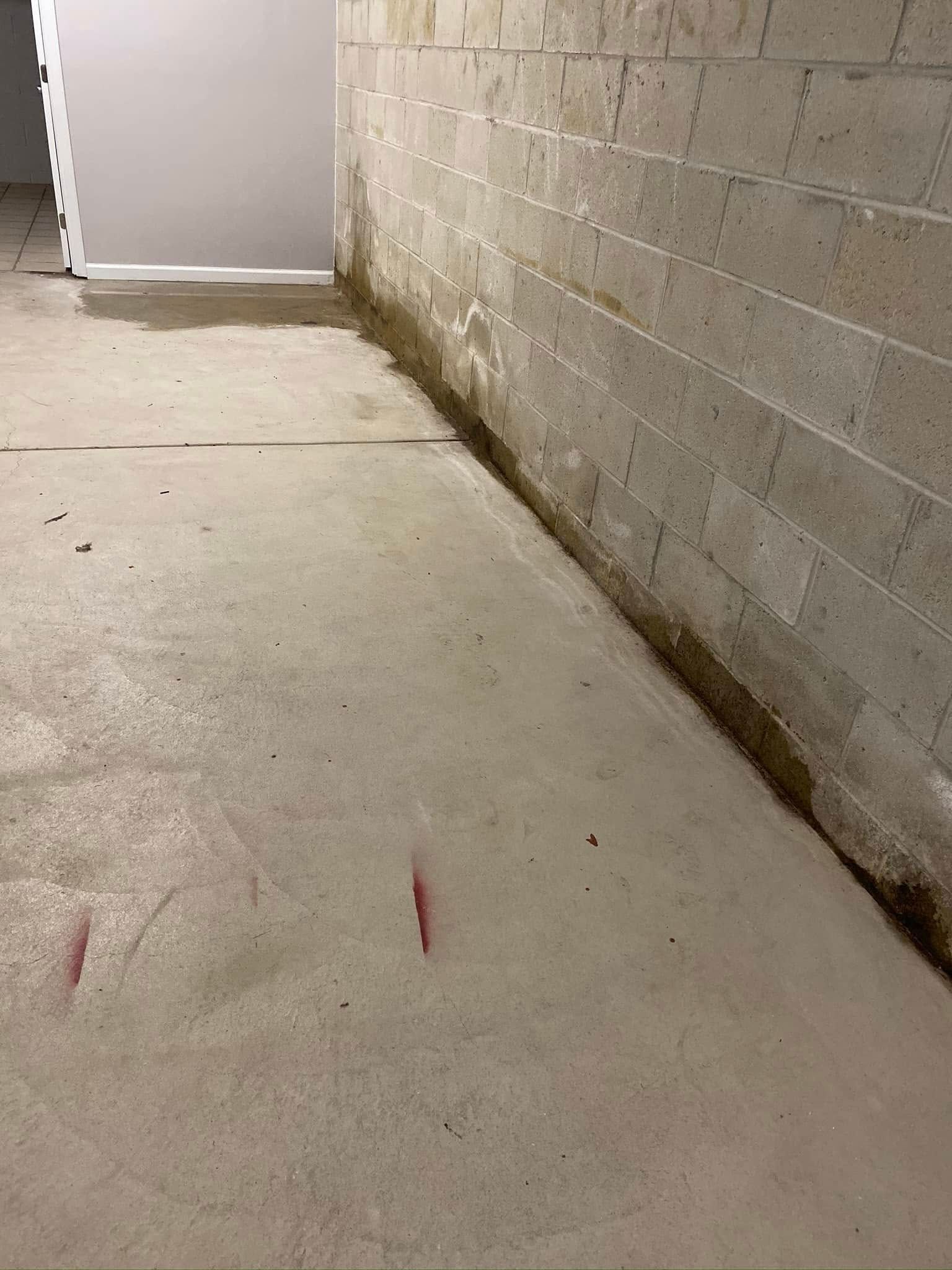 A concrete floor in a basement next to a brick wall.