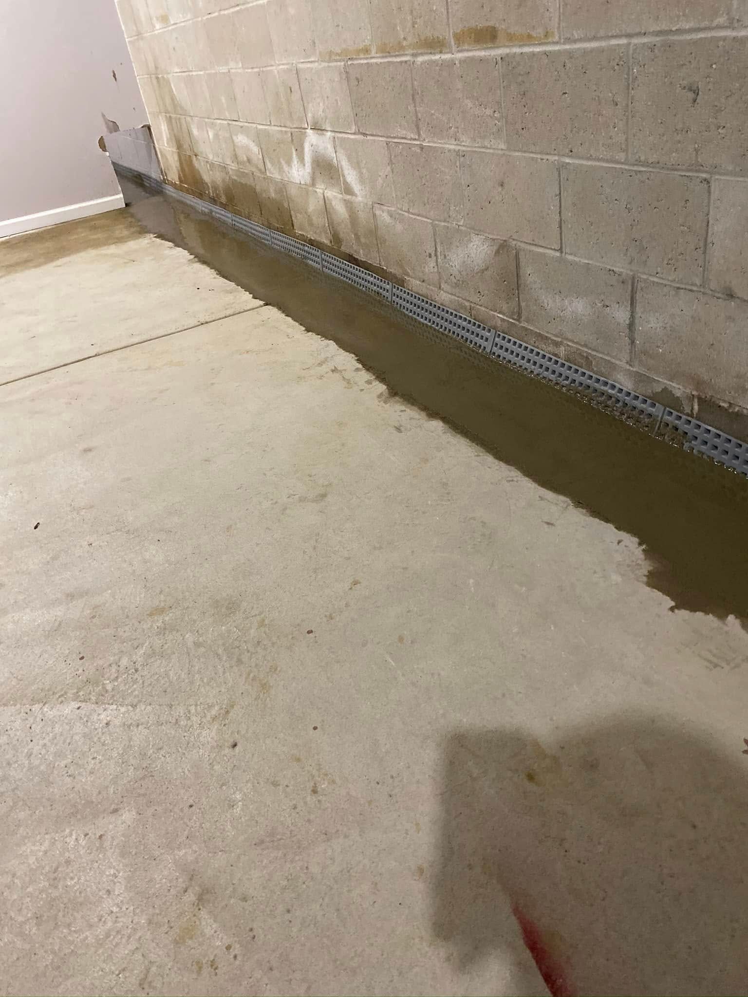 A concrete floor in a basement next to a brick wall.