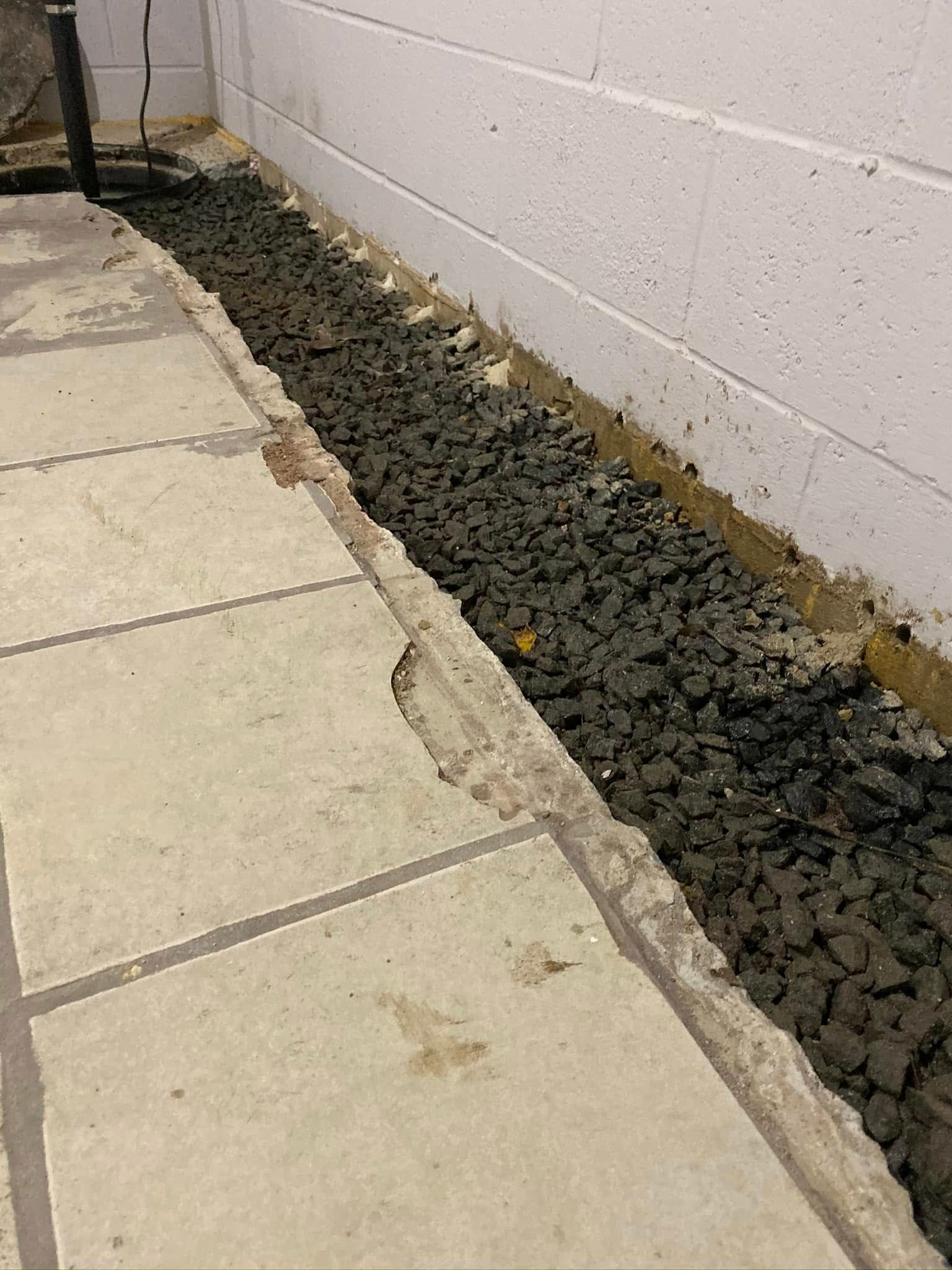 A pile of gravel is sitting next to a brick wall.