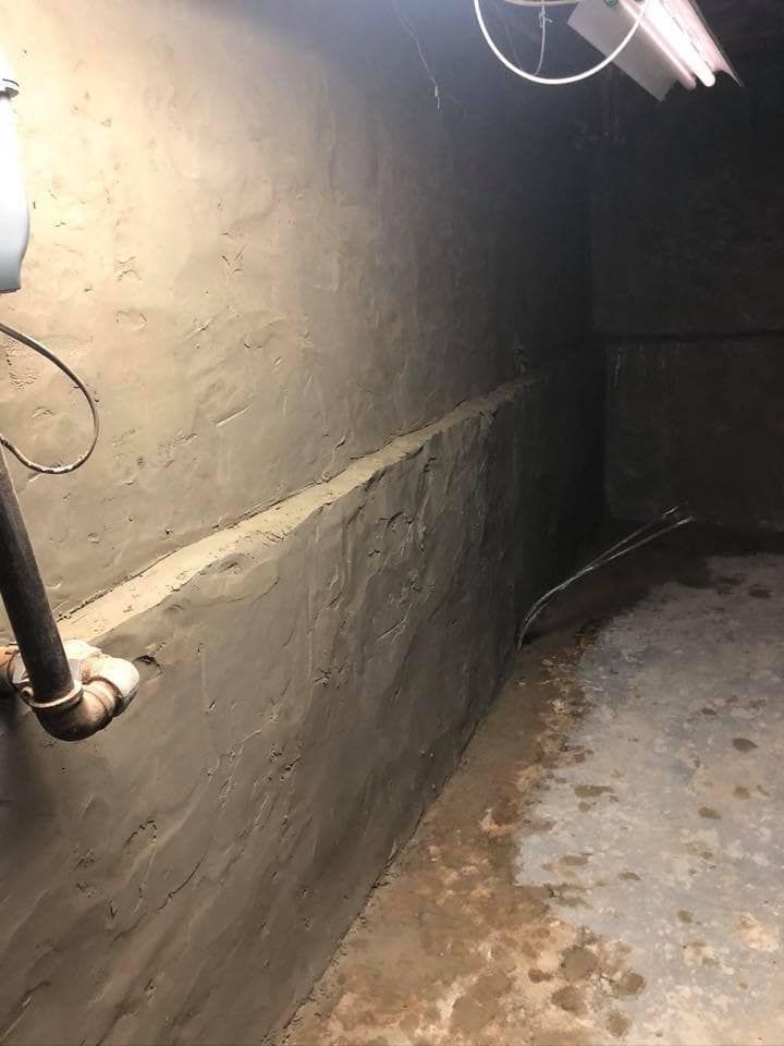 A dark room with a pipe and a light on the wall.