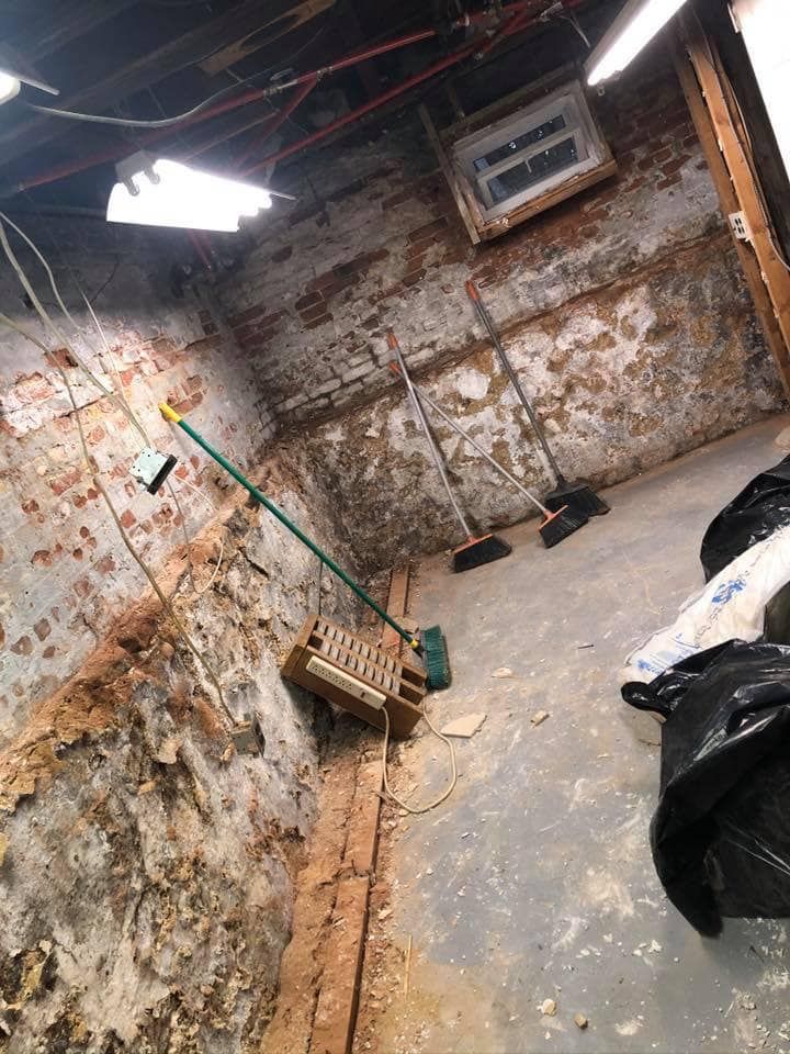 A room with a brick wall and a broom in it.