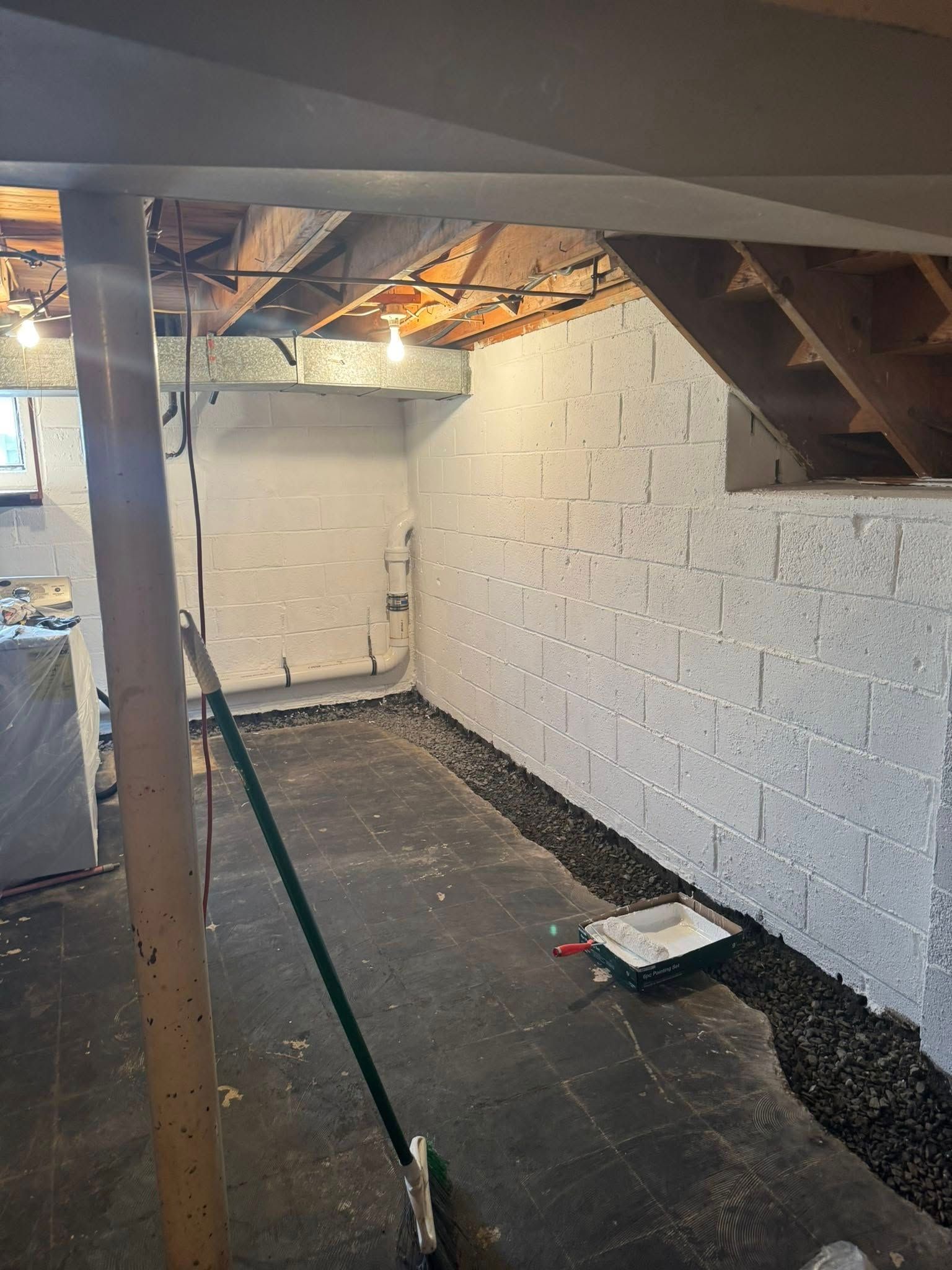 A basement with white brick walls and a green broom.