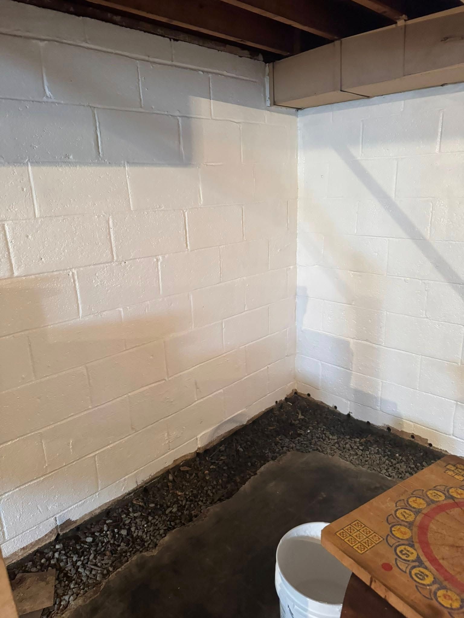 A basement with white brick walls and a bucket on the floor.