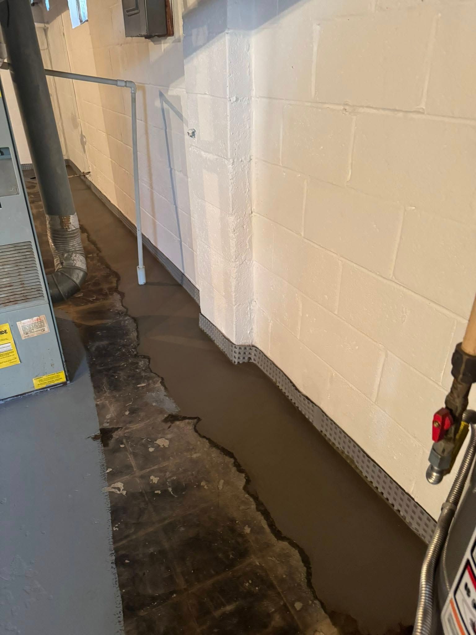 A person is standing in a basement next to a brick wall.