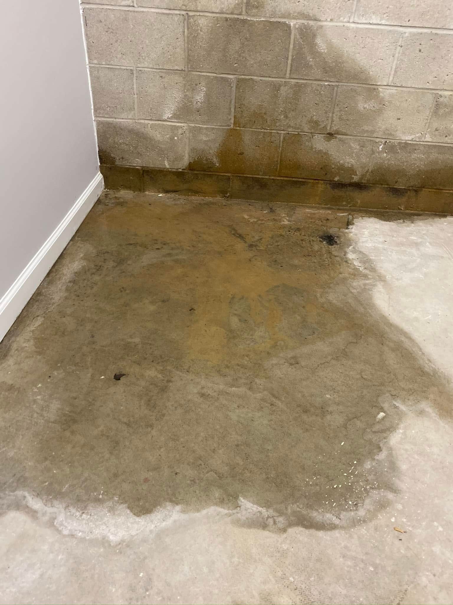 A concrete floor with water coming out of it next to a brick wall.